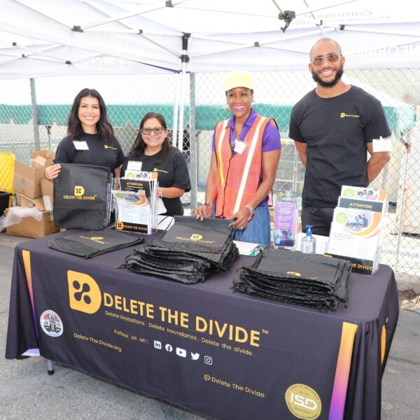 four DTD staff standing behind booth with drawstring bags