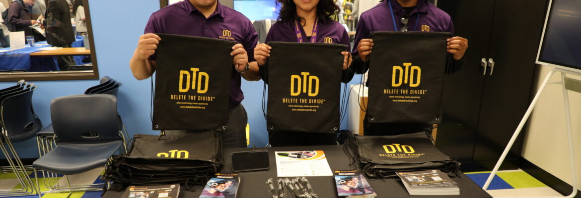 three interns holding drawstring bags behind a table with flyers and bags
