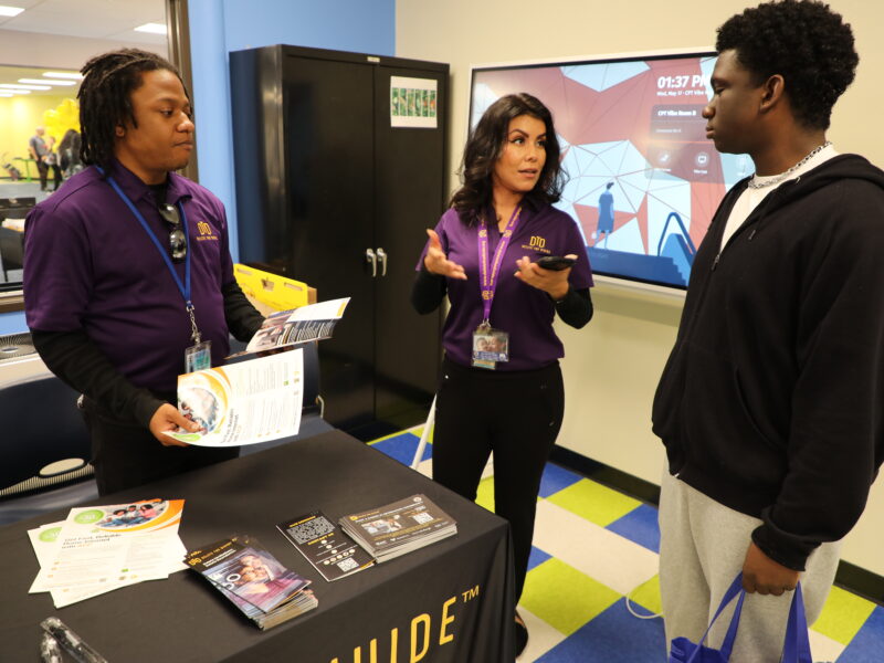 DTD staff holding flyers out for a student while another staff is talking