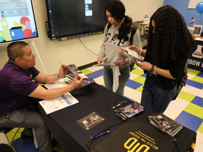 DTD staff holding up flyer while talking to two students