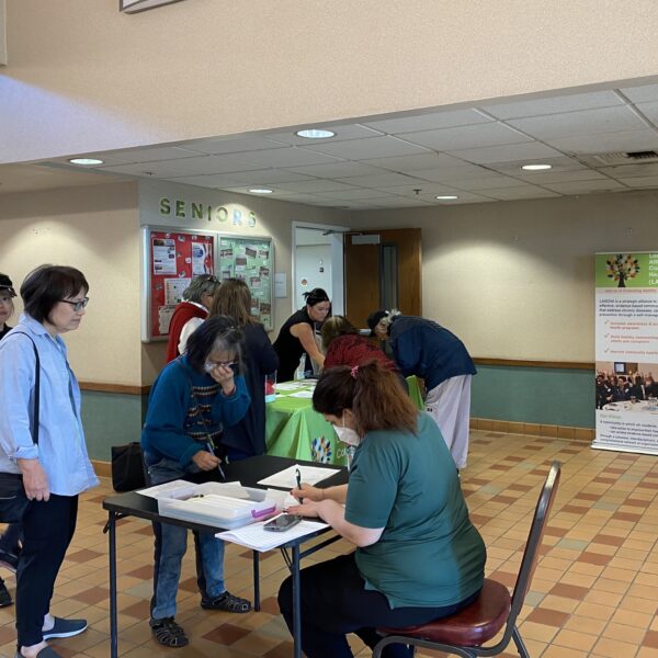 staff helping community members fill out laptop assessment forms