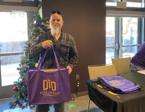 Man with beard holding DTD bag in front of a Christmas tree