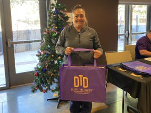 Woman holding a DTD bag in front of a Christmas tree