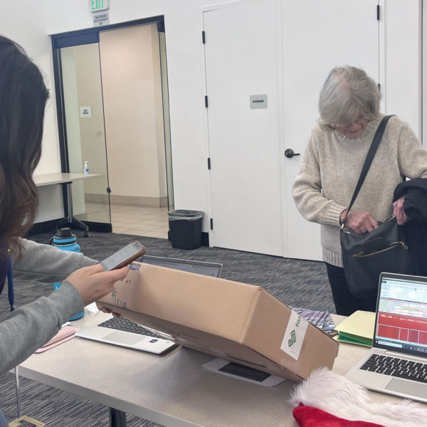 Intern checking out Laptop box. Veteran looking in bag.