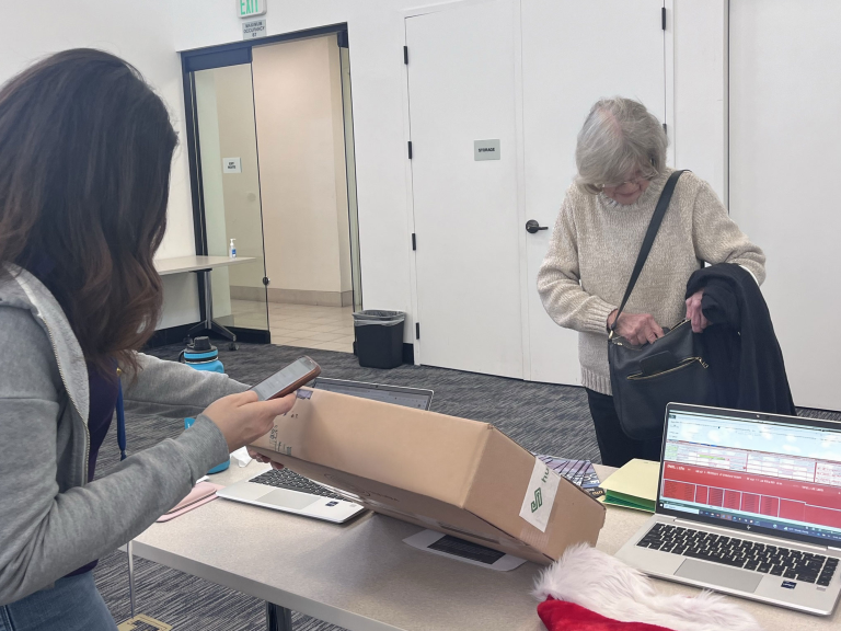 Intern checking out Laptop box. Veteran looking in bag.