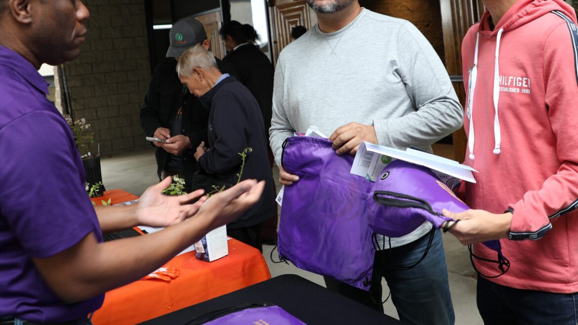 Intern handing bags to man in gray shirt and woman in pink hoodie