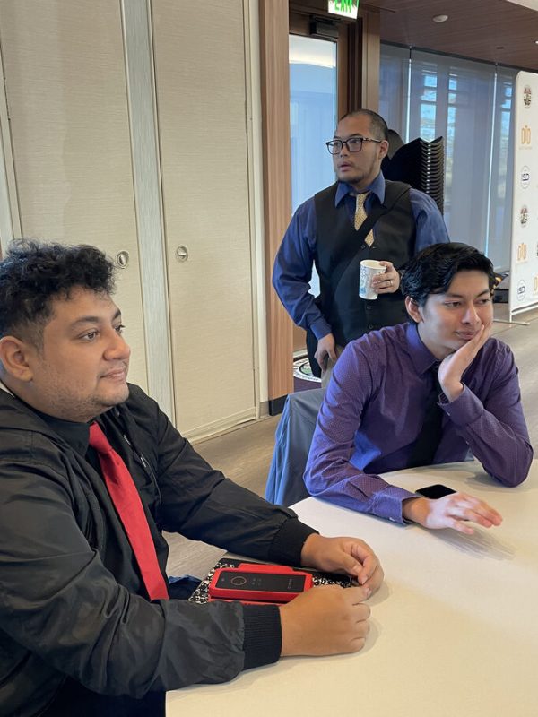 two DTD interns sitting at a table with one standing in the back