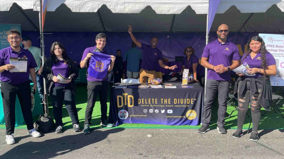 DTD staff holding bags and flyers while standing in front of the DTD booth