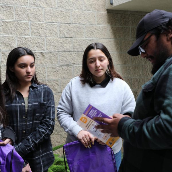 DTD staff pointing to a flyer and talking to two girls