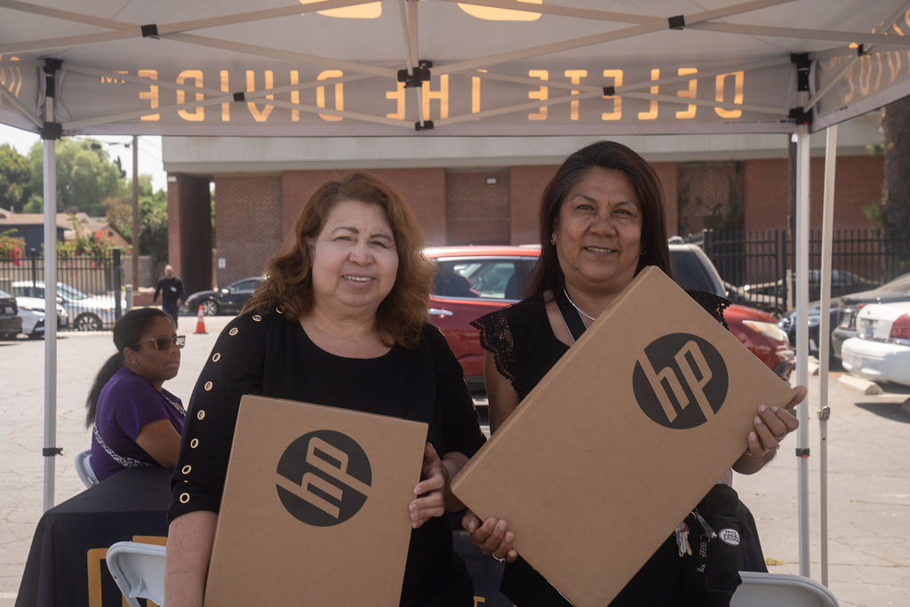 two women each holding a HP laptop box