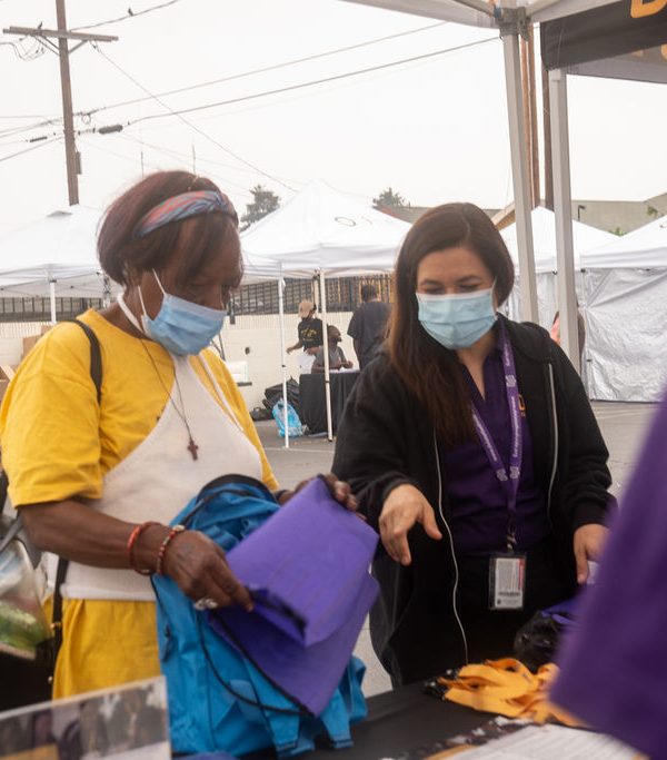 DTD staff giving a bag to a person and pointing to things on the table