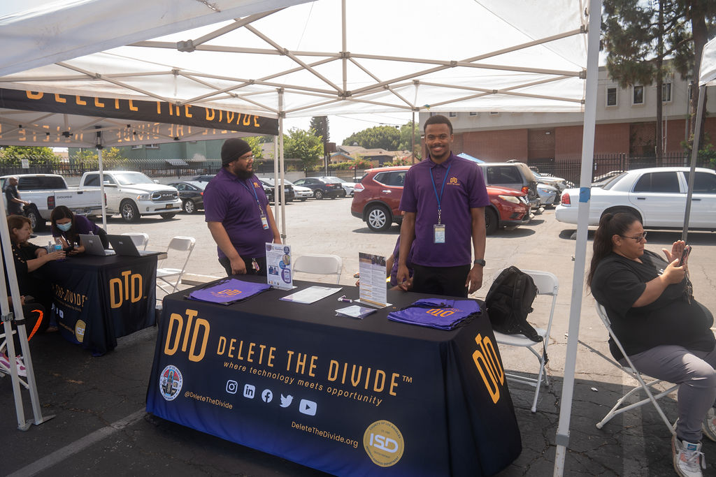 DTD staff standing behind a DTD booth table with bags and flyers