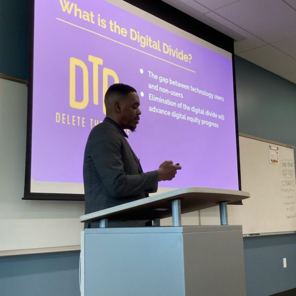 a DTD staff talking behind a podium on a slide presentation of what is the digital divide