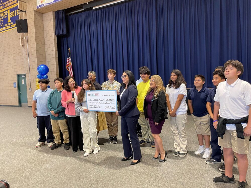 L.A. county employees holding a big check with students given to a middle school