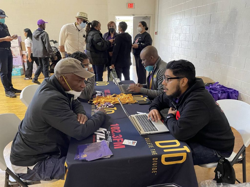 DTD staff on laptops helping participants with laptop distribution