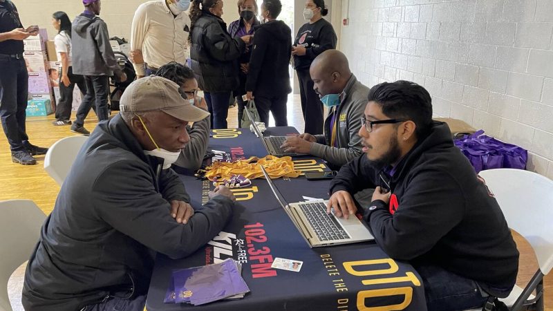 DTD staff on laptops helping participants with laptop distribution