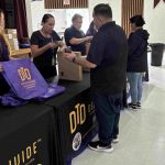 DTD staff handing laptop to Lynwood resident